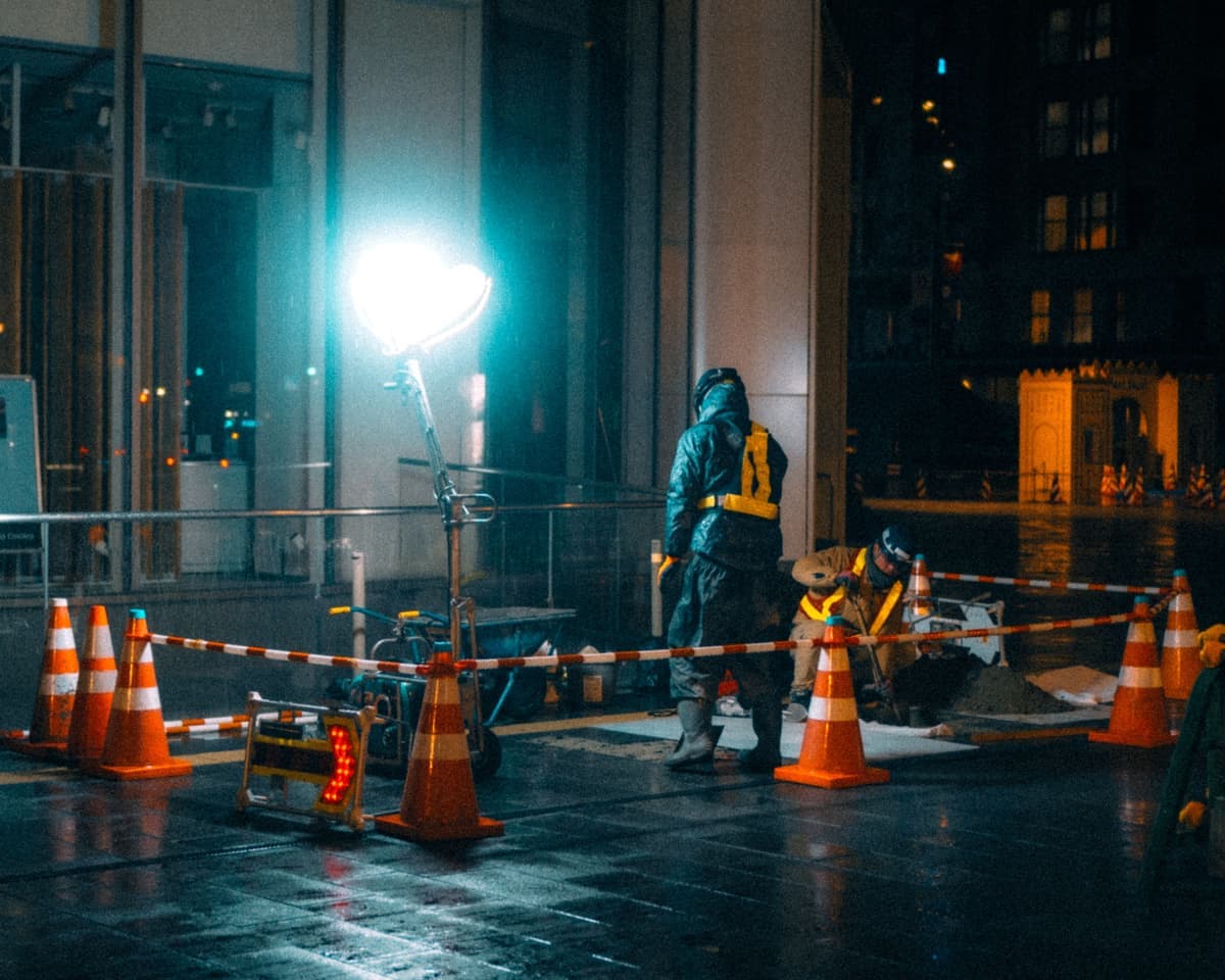 A worker in a hard hat on a site lit at night