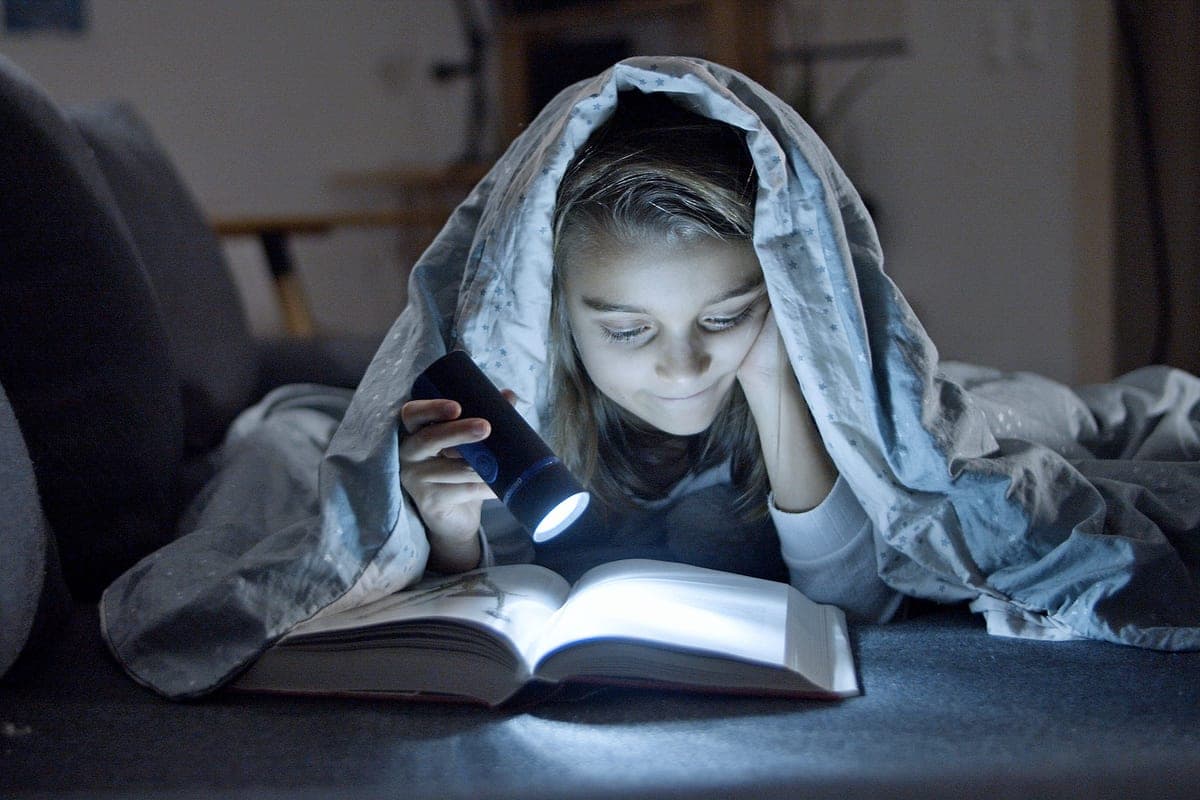 A child holding a small flashlight in a dark room
