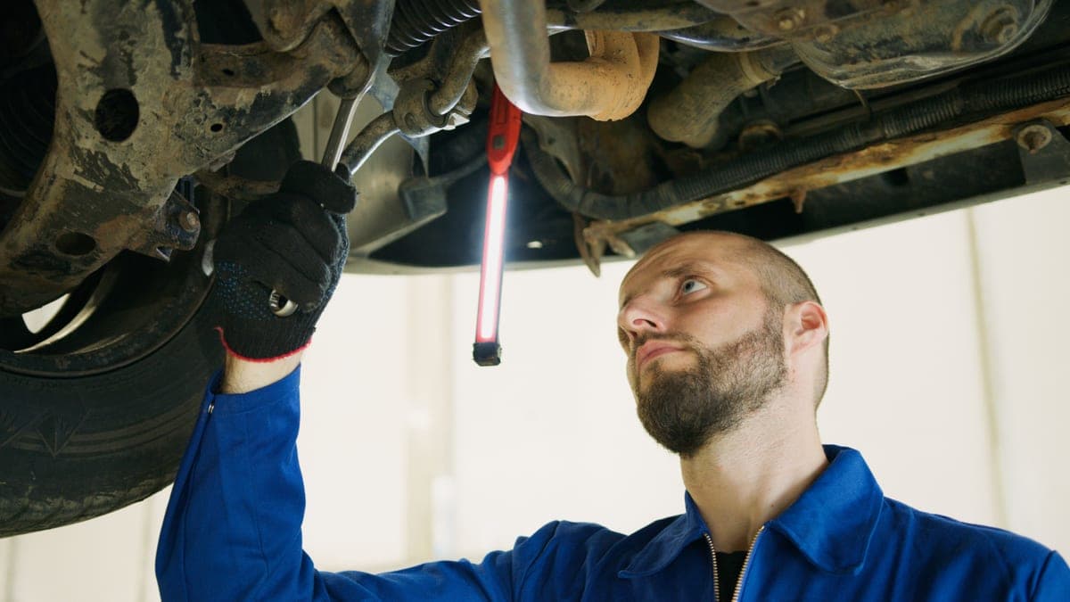 A mechanic working under a vehicle with a work light